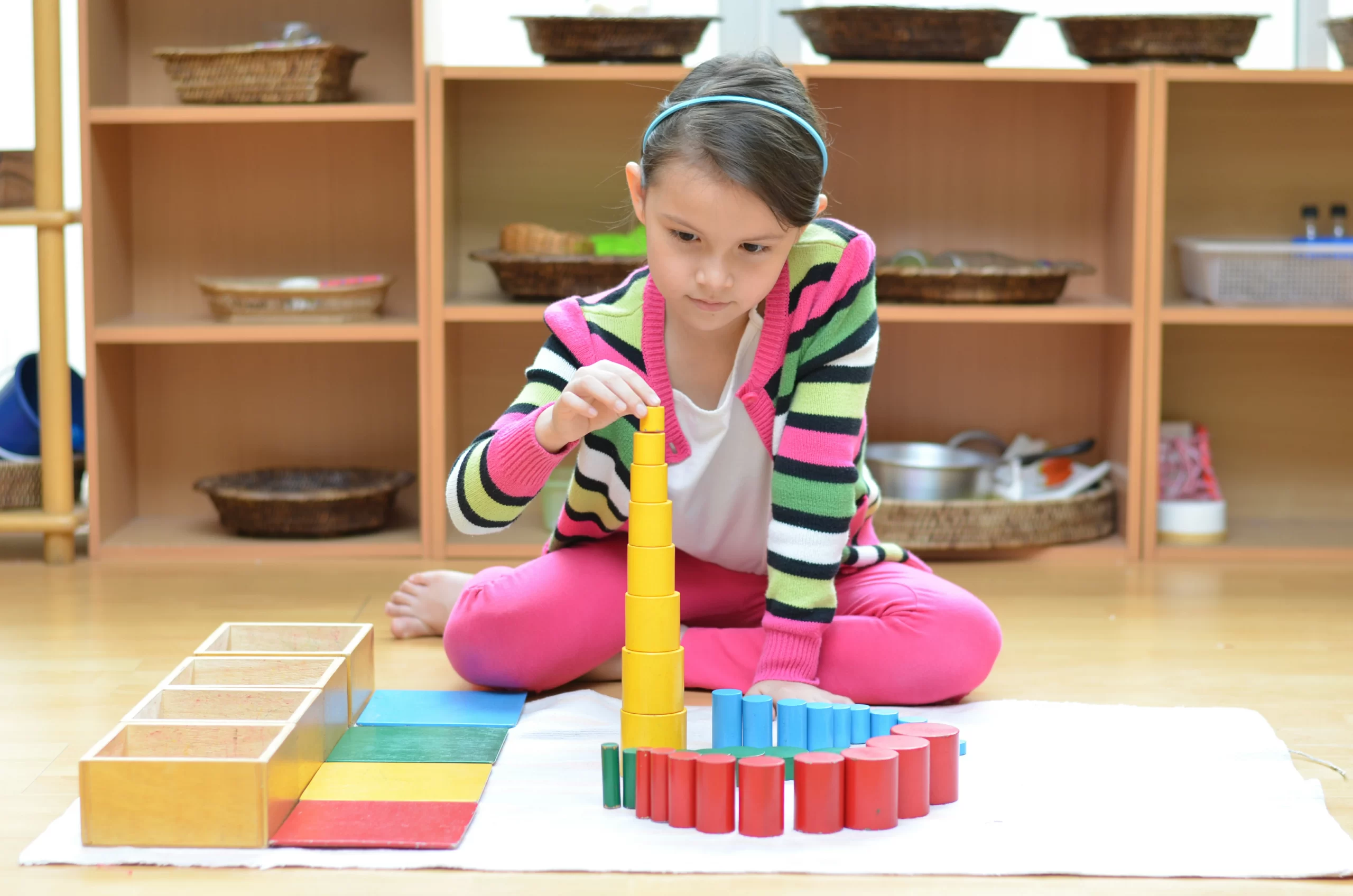 A child arranging colourful Montessori cylinders
